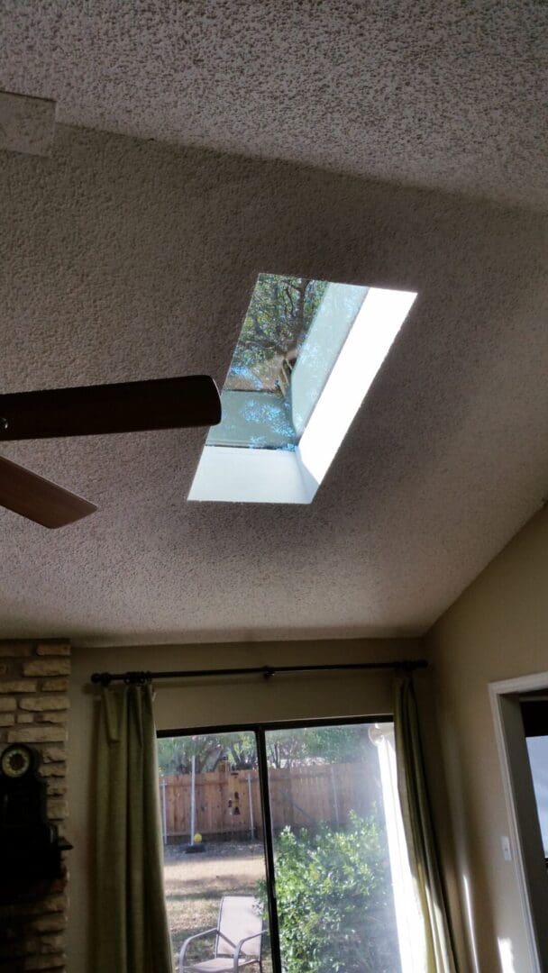 A skylight in the ceiling of a room with a window.