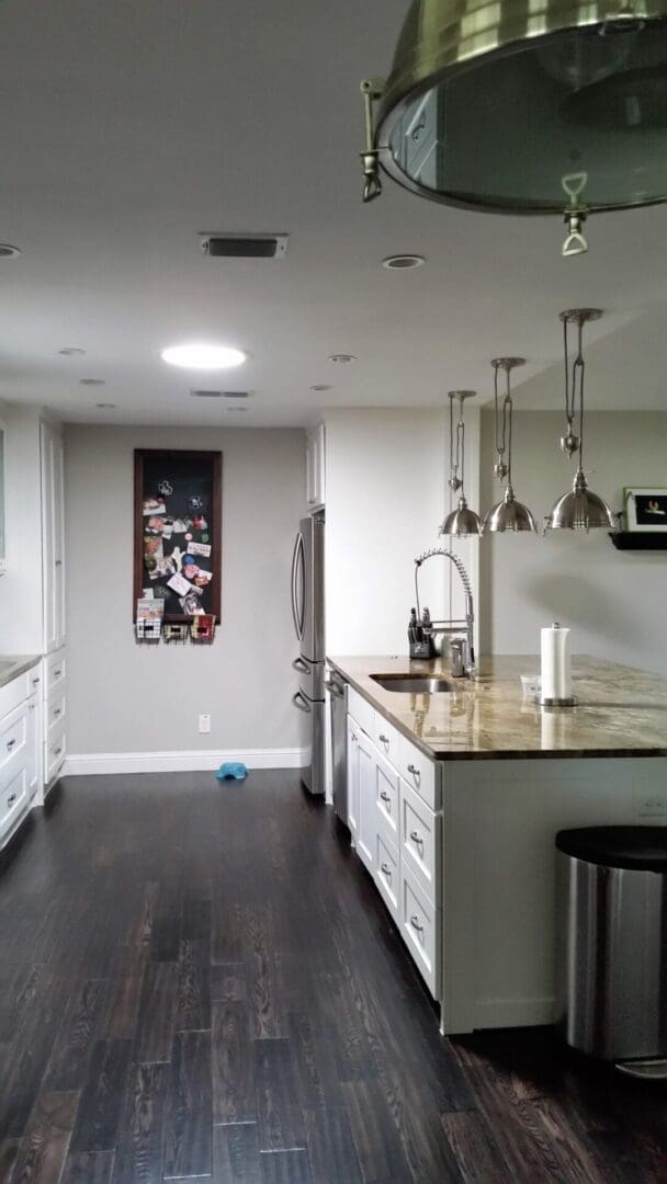 A kitchen with white cabinets and black floor