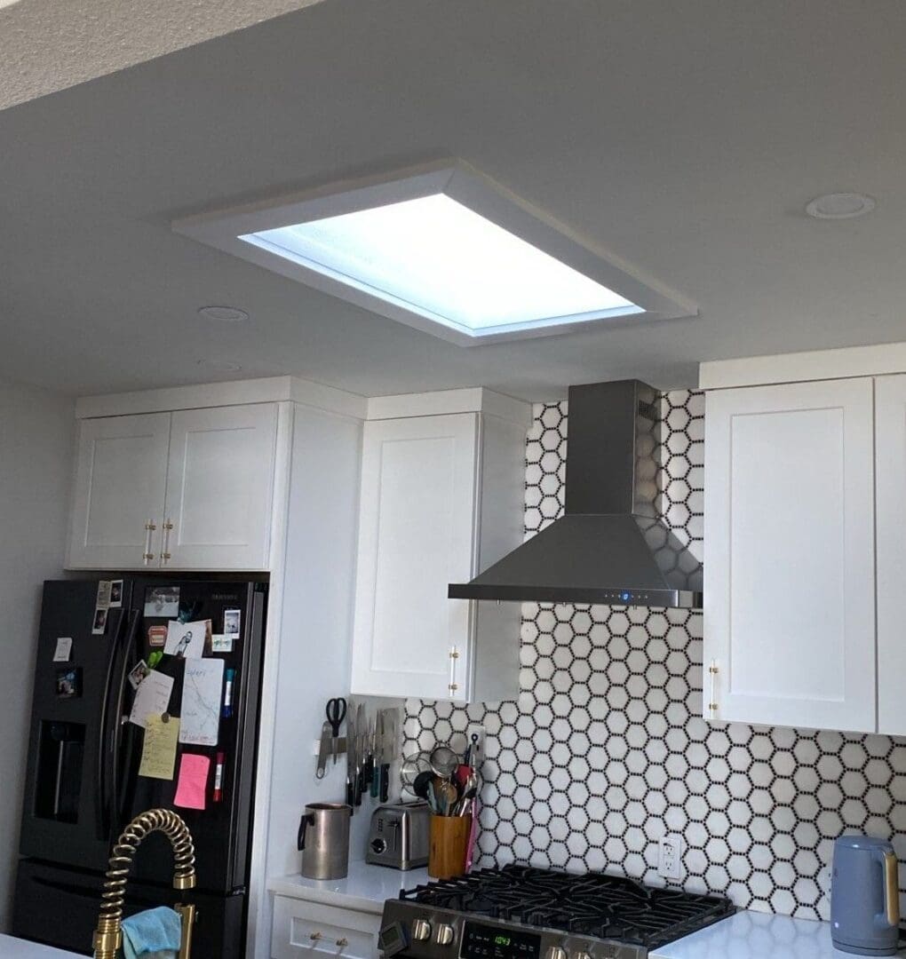 A kitchen with white cabinets and a black refrigerator.