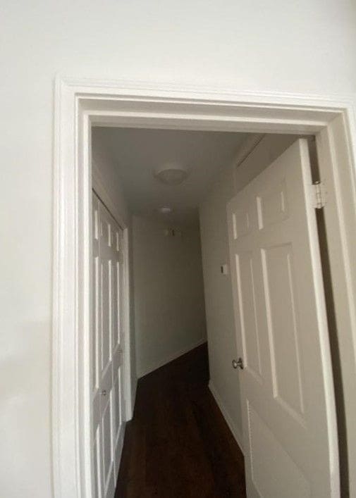 A hallway with two doors and a wooden floor.