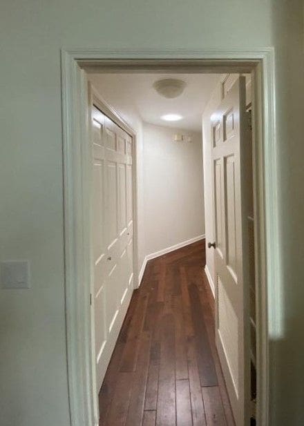 A hallway with two doors and a wooden floor.