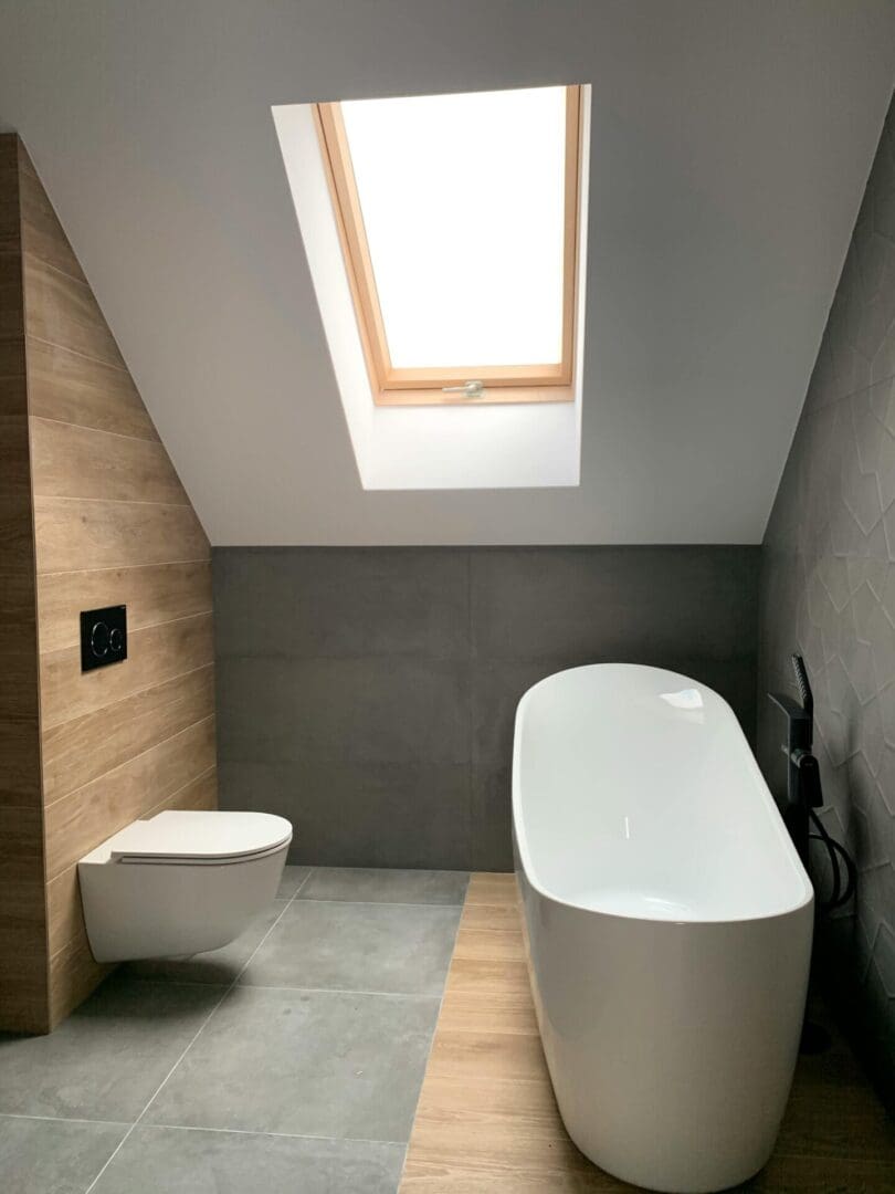 A bathroom with a toilet, bathtub and skylight.